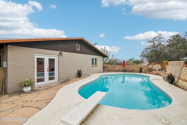 view of pool with a fenced in pool, a patio, a fenced backyard, french doors, and a diving board