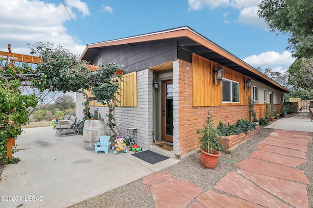 exterior space with brick siding, a patio, and fence