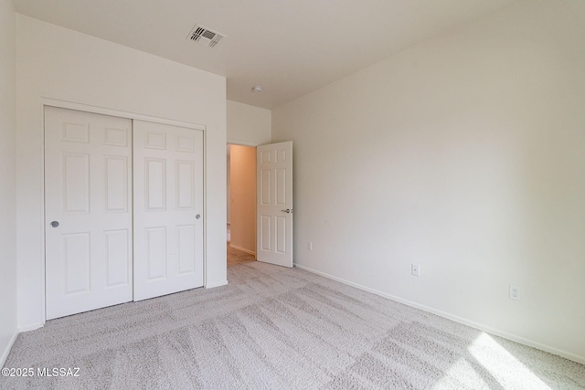 unfurnished bedroom with light carpet and a closet