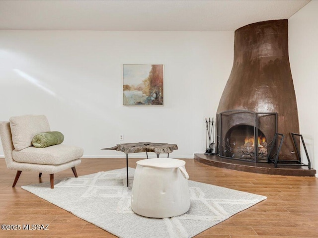 sitting room featuring a large fireplace and wood-type flooring