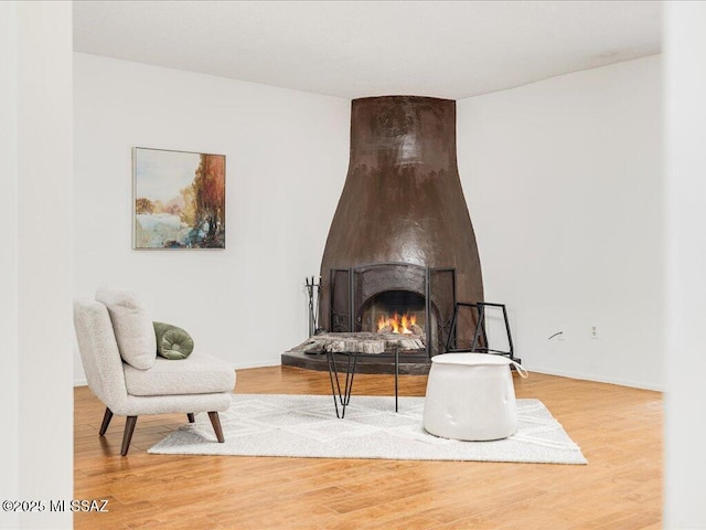 living area featuring a large fireplace and hardwood / wood-style flooring