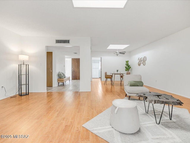 living room with hardwood / wood-style flooring, ceiling fan, and a skylight