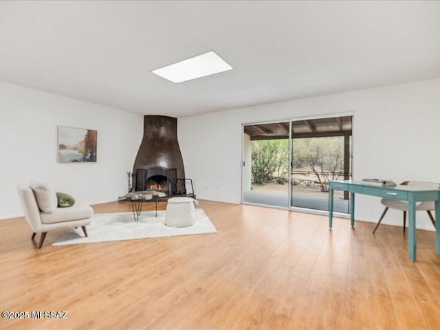 sitting room featuring a skylight and light hardwood / wood-style floors