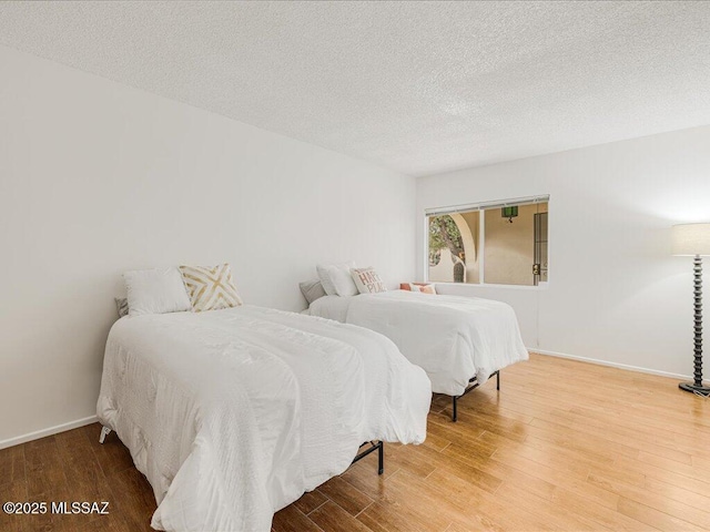 bedroom with a textured ceiling and wood-type flooring