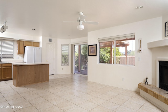 kitchen featuring a center island, white refrigerator, sink, ceiling fan, and light tile patterned floors