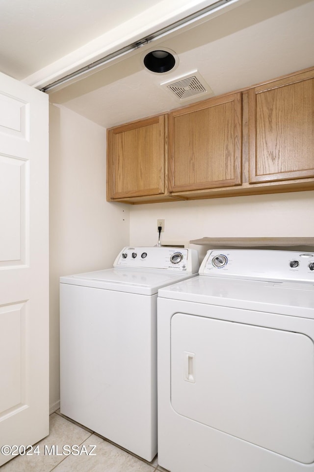 clothes washing area with cabinets, light tile patterned floors, and independent washer and dryer