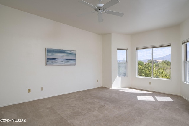 spare room with a mountain view, light colored carpet, and ceiling fan