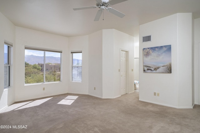 spare room with ceiling fan, light colored carpet, and a mountain view