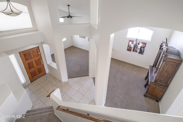 foyer with a high ceiling, light tile patterned floors, and ceiling fan