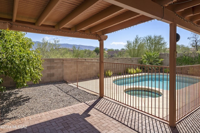 view of swimming pool featuring a mountain view, a patio area, and an in ground hot tub