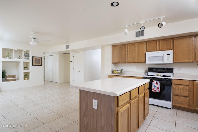 kitchen featuring white appliances, ceiling fan, light tile patterned floors, built in features, and a center island