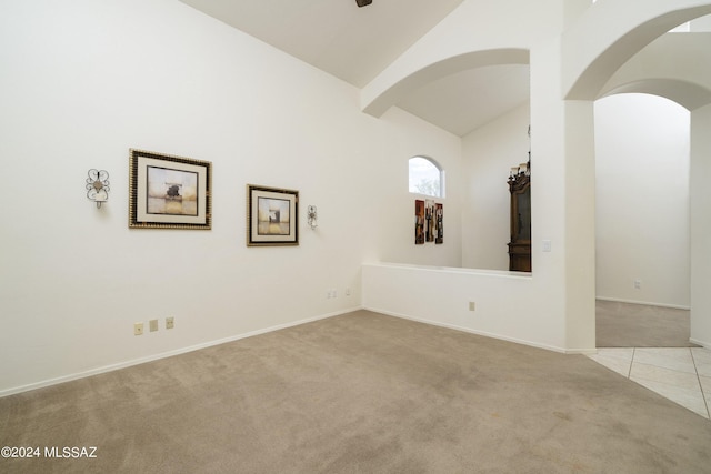 spare room with light carpet and high vaulted ceiling