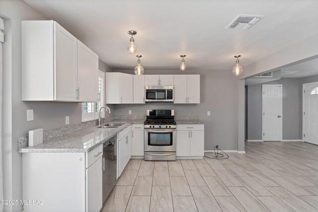 kitchen featuring appliances with stainless steel finishes, white cabinetry, and sink