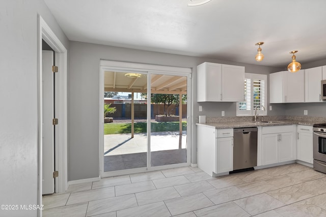 kitchen with light stone countertops, white cabinetry, sink, and appliances with stainless steel finishes