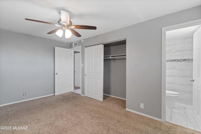 unfurnished bedroom featuring carpet flooring, ensuite bath, ceiling fan, and a closet