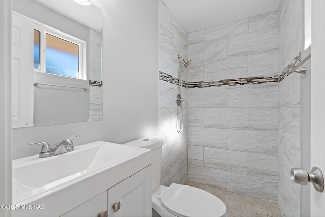 bathroom with vanity, toilet, and tiled shower