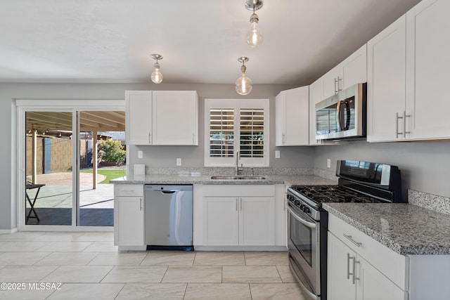 kitchen featuring light stone countertops, appliances with stainless steel finishes, sink, decorative light fixtures, and white cabinets