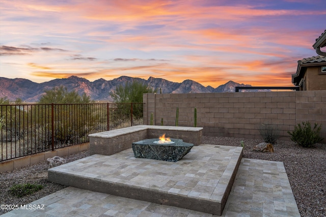 patio terrace at dusk featuring a mountain view and a fire pit