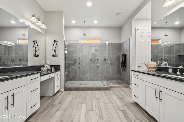 bathroom featuring tiled shower and vanity