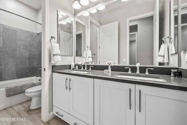 full bathroom featuring vanity, tiled shower / bath combo, and toilet