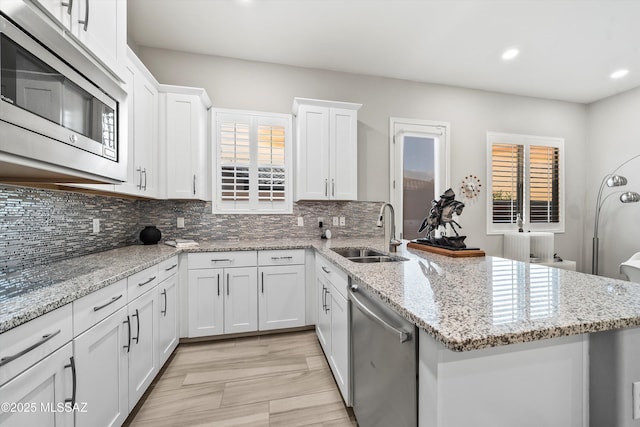 kitchen with light stone countertops, sink, white cabinets, and appliances with stainless steel finishes