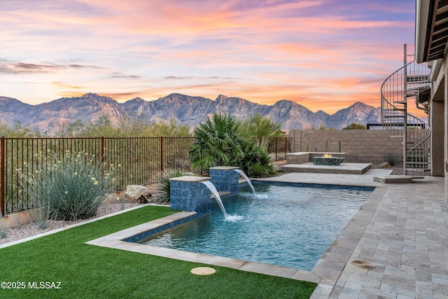 pool at dusk featuring a mountain view and pool water feature