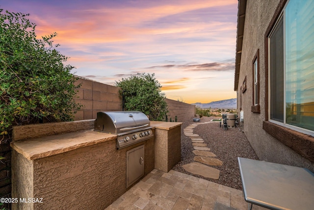 patio terrace at dusk featuring a mountain view and area for grilling