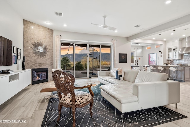 living room featuring ceiling fan, a fireplace, and sink