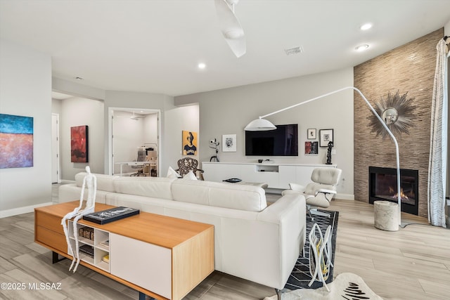 living room featuring ceiling fan, a fireplace, and hardwood / wood-style flooring