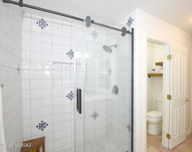 bathroom featuring tile patterned flooring, toilet, and a shower with door