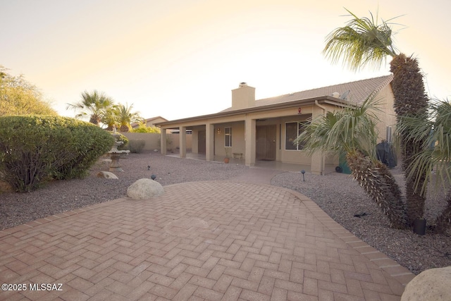 back house at dusk with a patio area