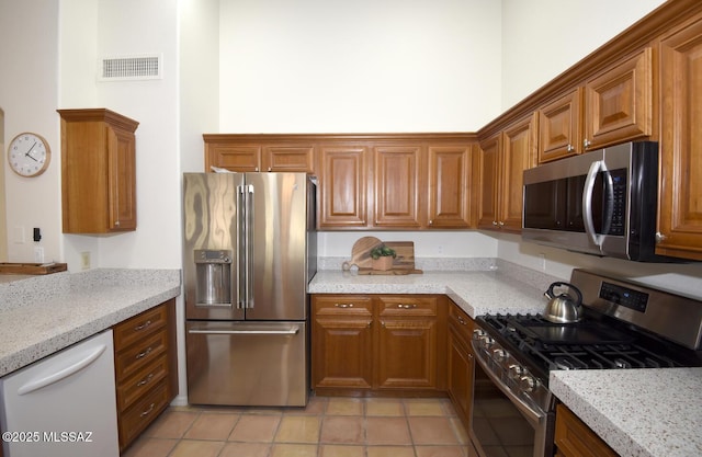 kitchen featuring light tile patterned floors, stainless steel appliances, and light stone counters