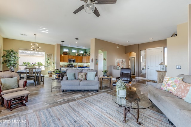 living room featuring wood-type flooring, sink, and ceiling fan with notable chandelier