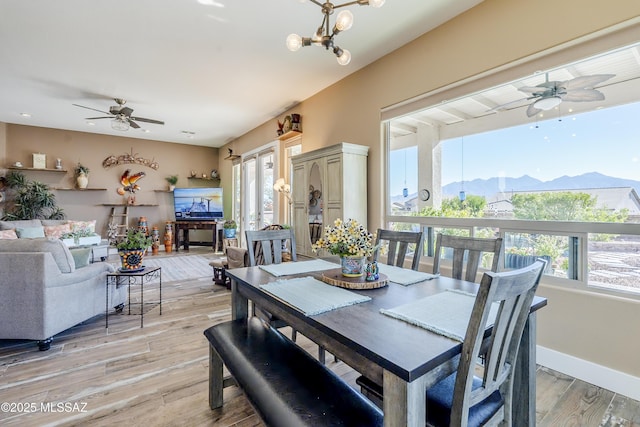 dining space with ceiling fan with notable chandelier and light wood-type flooring