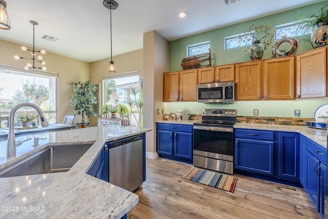 kitchen with appliances with stainless steel finishes, light hardwood / wood-style flooring, hanging light fixtures, and sink