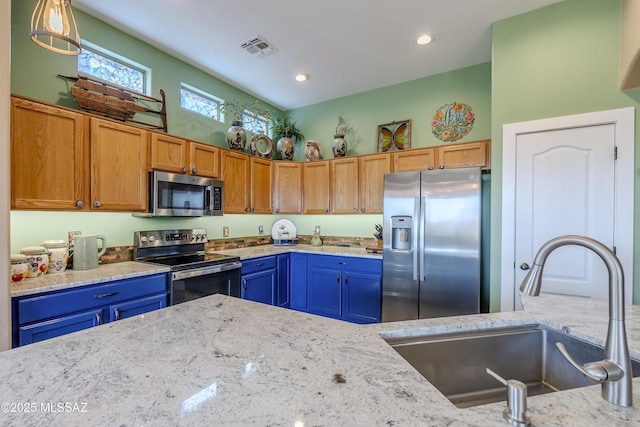 kitchen with light stone countertops, appliances with stainless steel finishes, hanging light fixtures, and sink