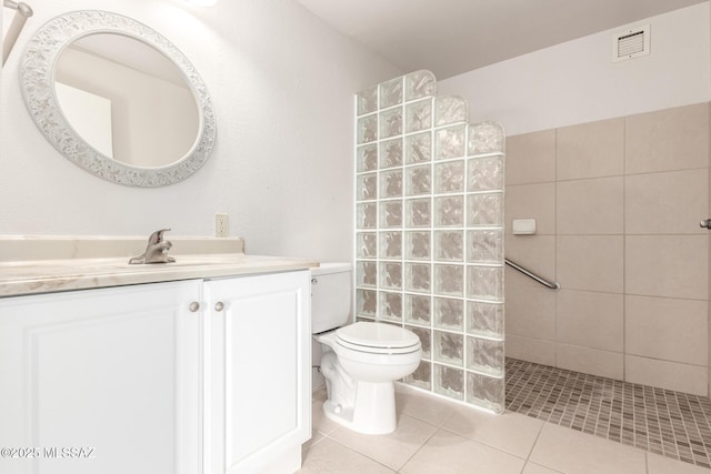 bathroom with tile patterned flooring, vanity, tiled shower, and toilet