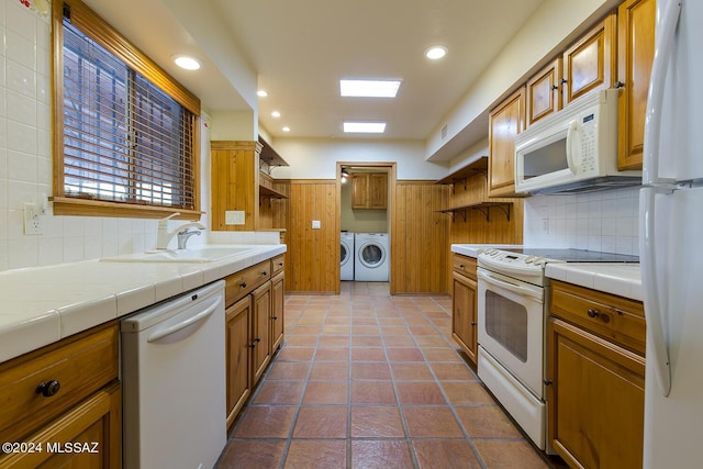 kitchen featuring tile counters, washing machine and dryer, white appliances, and sink