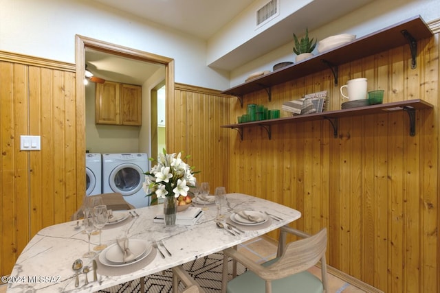 dining space with wood walls and washing machine and dryer