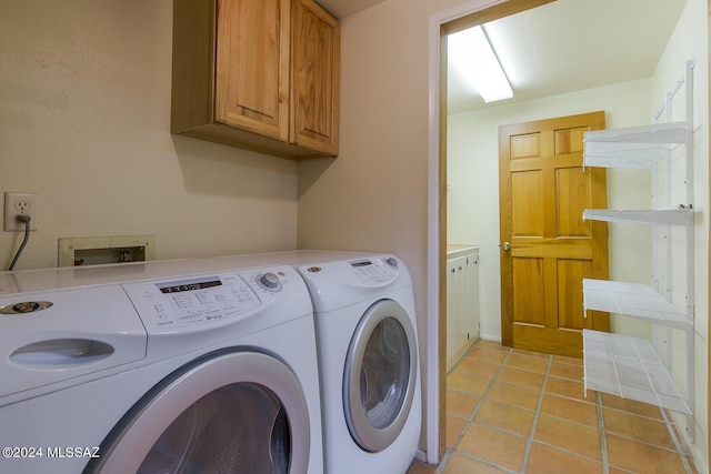 clothes washing area with washer and clothes dryer, light tile patterned flooring, and cabinets