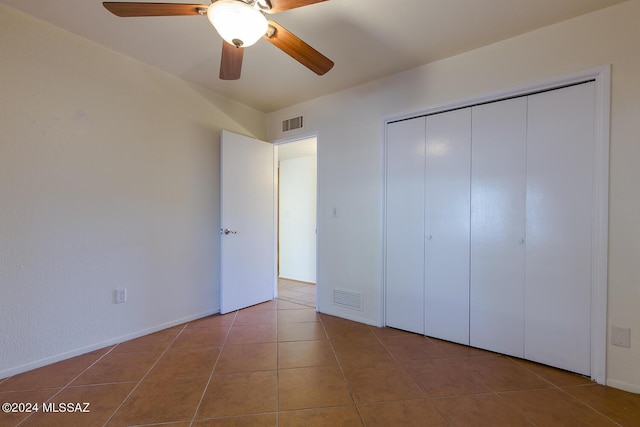 unfurnished bedroom featuring a closet, tile patterned floors, and ceiling fan