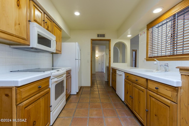 kitchen with tasteful backsplash, tile counters, white appliances, and sink