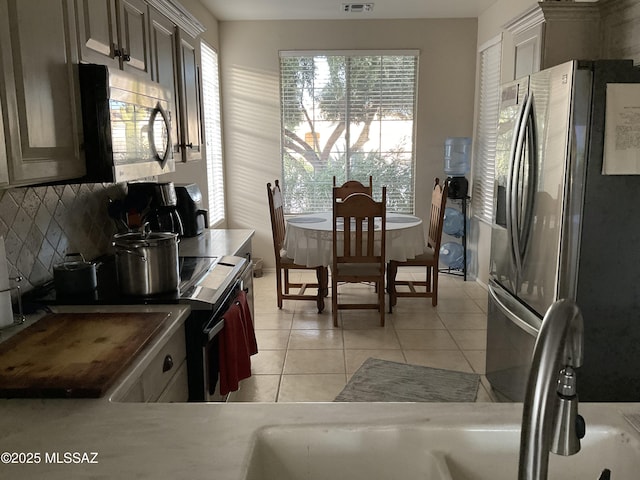 kitchen featuring backsplash, light tile patterned floors, and appliances with stainless steel finishes