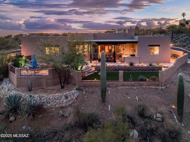 back house at dusk with an outdoor kitchen and a patio area