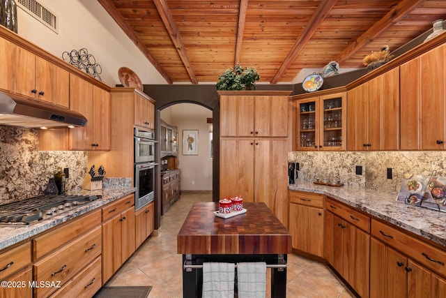 kitchen featuring light stone countertops, backsplash, stainless steel appliances, beam ceiling, and wooden ceiling