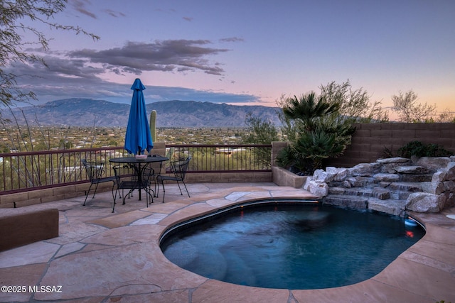 pool at dusk with pool water feature and a mountain view