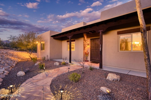 exterior entry at dusk featuring a patio