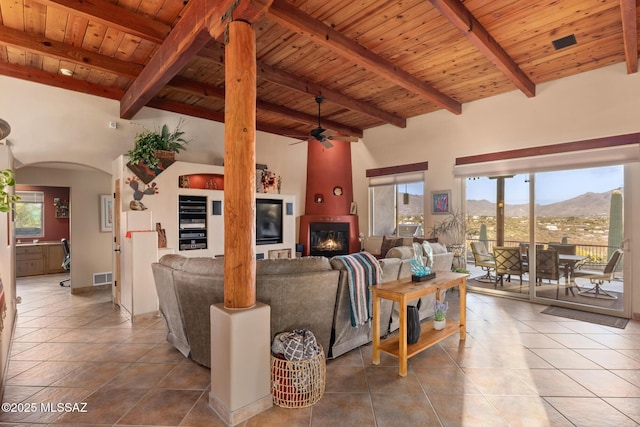 tiled living room with ceiling fan, wooden ceiling, beamed ceiling, high vaulted ceiling, and a fireplace