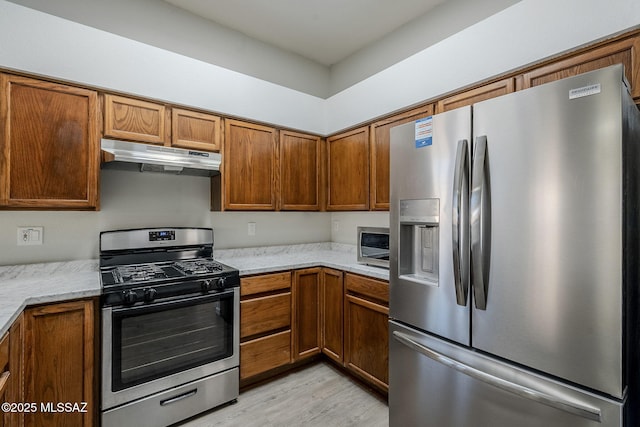 kitchen with light hardwood / wood-style floors, light stone countertops, and appliances with stainless steel finishes