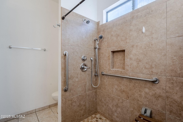 bathroom featuring tile patterned floors, toilet, and a tile shower